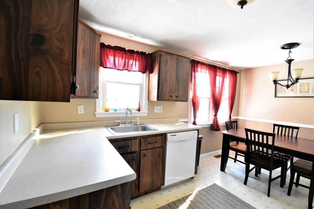 38 Juniper Road, Unit R Derry, NH 03038 - Photo 7 of 22 a kitchen with a sink a window and chairs