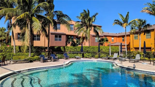 a view of a swimming pool with a lawn chairs and palm trees