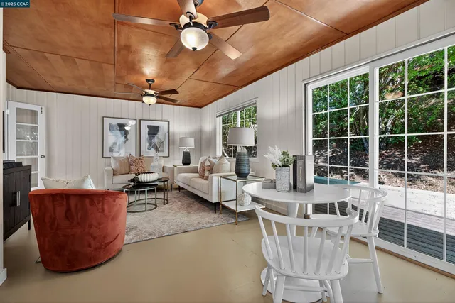 a living room with furniture a ceiling fan and a large window