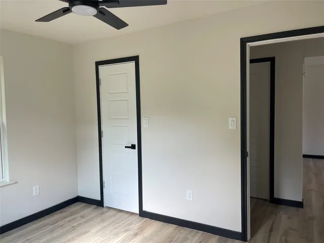 an empty room with wooden floor cabinet and a ceiling fan