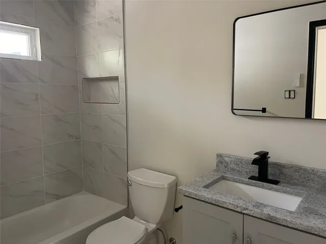 a bathroom with a granite countertop toilet sink and mirror