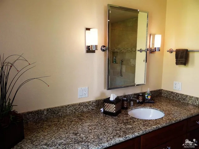 a bathroom with a granite countertop sink and a mirror