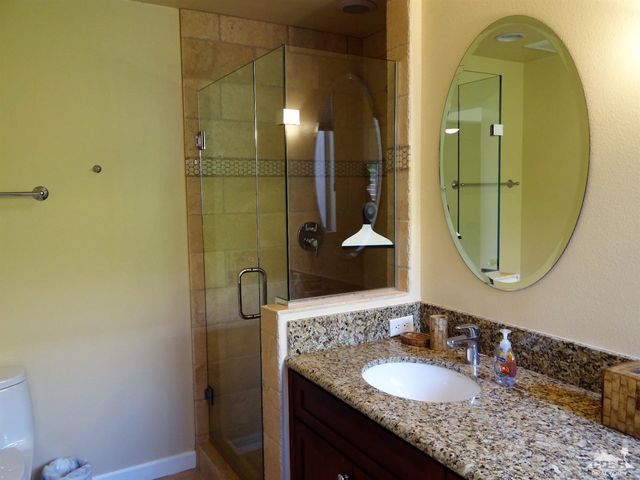 a bathroom with a granite countertop sink a mirror and a shower