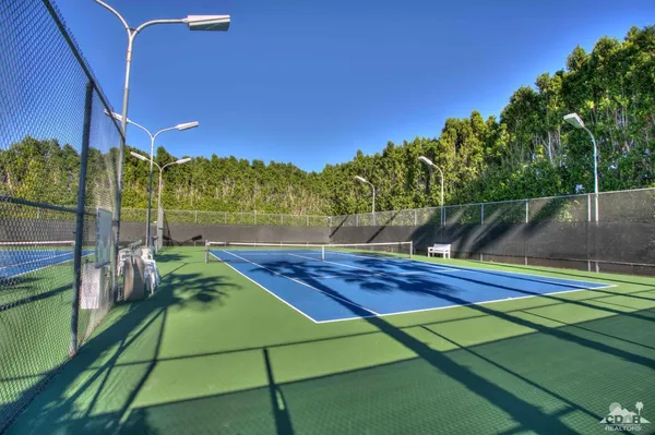 a view of a tennis ground with large trees
