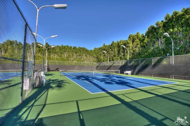 a view of a tennis ground with large trees
