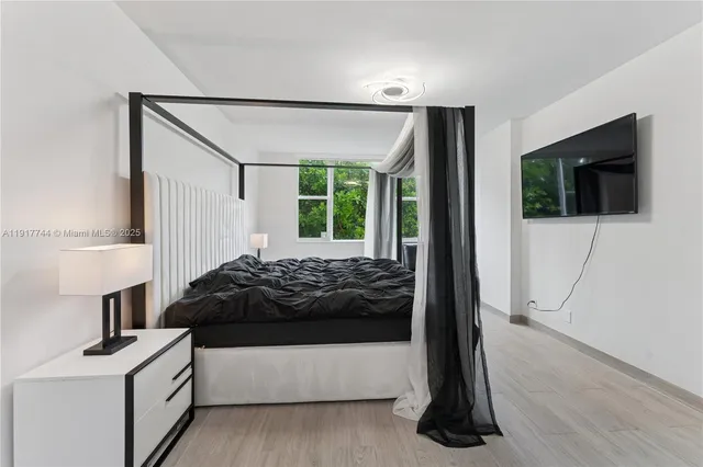 a bedroom with a bed window and a flat screen tv