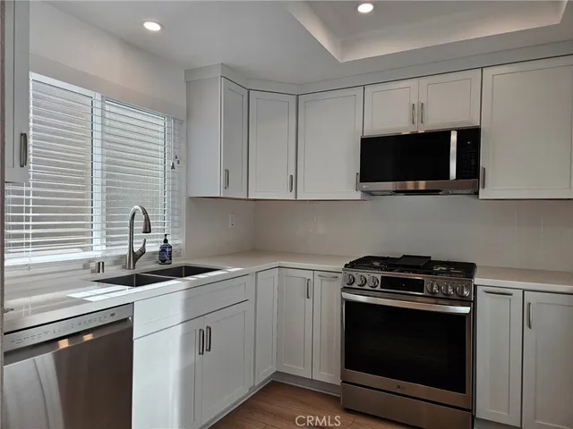 a kitchen with stainless steel appliances granite countertop white cabinets a sink and a stove