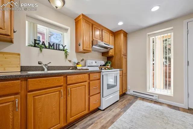 a kitchen with stainless steel appliances granite countertop a refrigerator a sink dishwasher and wooden cabinets with wooden floor