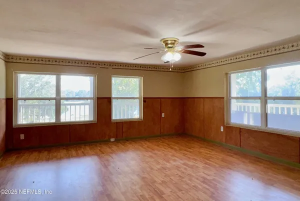 an empty room with wooden floor and windows