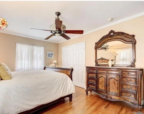 a bedroom with a bed and dresser with wooden floor