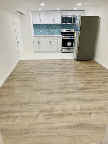 a view of kitchen with stainless steel appliances wooden cabinets and a refrigerator