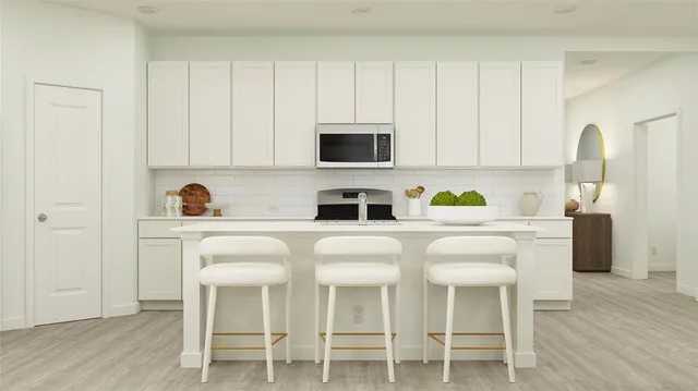 a white kitchen with a stove a sink and white cabinets