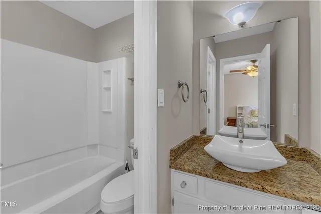 a bathroom with a granite countertop sink a toilet and bathtub