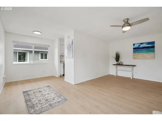 a view of an empty room with window and wooden floor