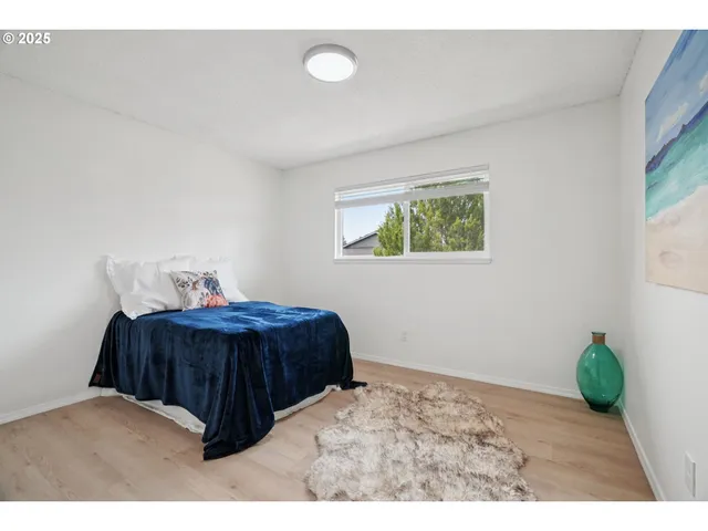 a bedroom with a bed window and painting on the wall