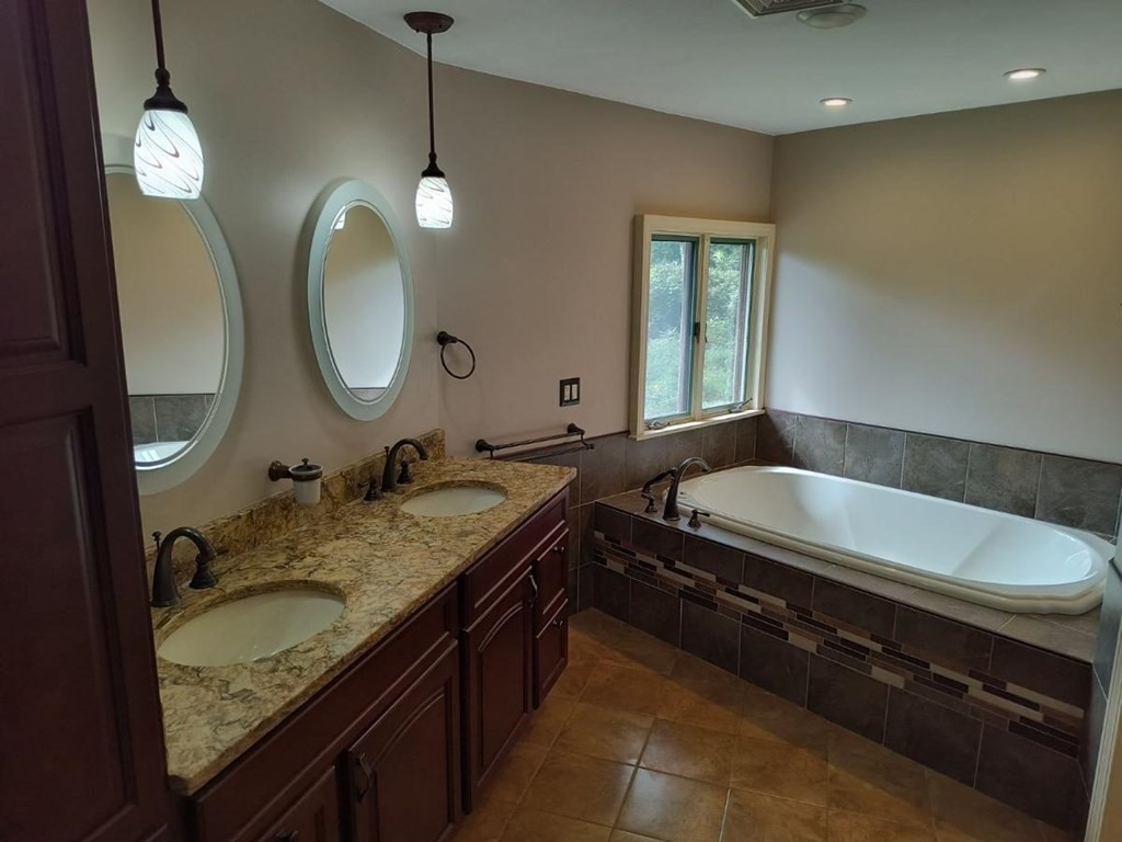 8 Birch Bluff Road Montgomery, MA 01085 - Photo 27 of 41 a bathroom with a granite countertop bathtub a double vanity sink and a mirror