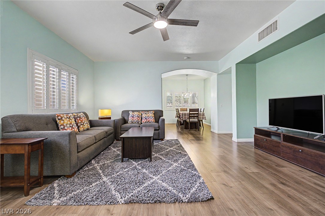 2153 Quarry Ridge Street, Unit 103 Las Vegas, NV 89117 - Photo 1 of 42 A well-lit interior space with hardwood flooring extends into a dining area, featuring a ceiling fan for comfort.