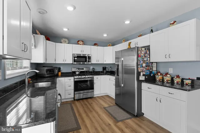 a kitchen with a refrigerator a stove top oven a sink and cabinets