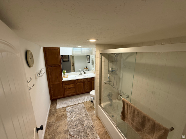 1360 Carterville Road Orem, UT 84097 - Photo 21 of 41 Tile flooring, wood-finish cabinetry, built-in bathtub with shower, glass shower enclosure, and a vanity with an integrated sink