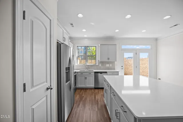 a large kitchen with stainless steel appliances a large counter top and a refrigerator