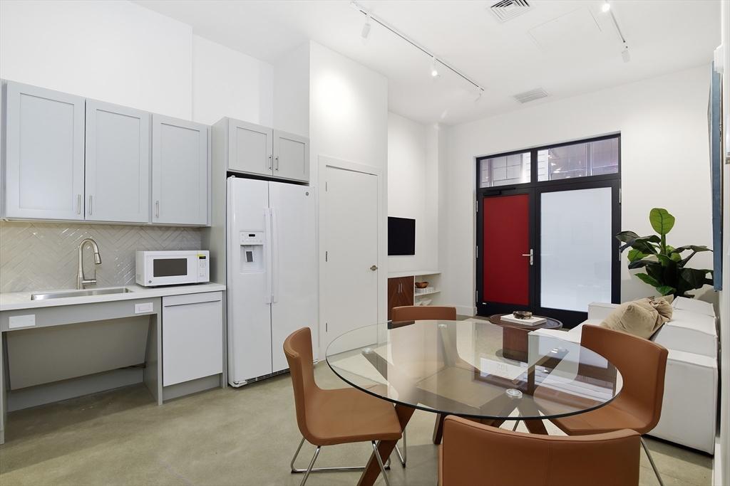 10 Stonley Road, Unit 102 Boston, MA 02130 - Photo 4 of 13 a kitchen with stainless steel appliances granite countertop a dining table chairs refrigerator and sink