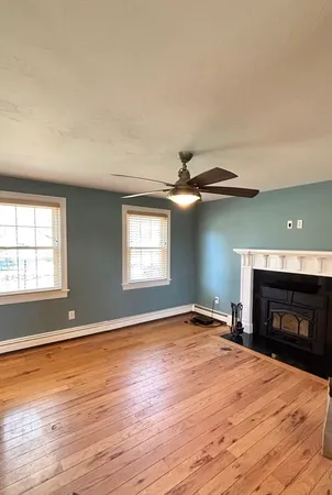 an empty room with wooden floor fireplace and windows