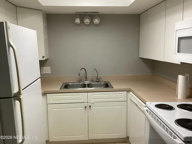 a kitchen with a sink a refrigerator and cabinets