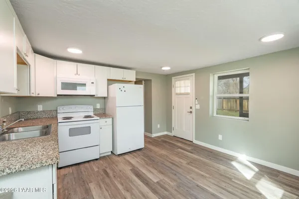 a kitchen with a refrigerator a stove top oven and white cabinets