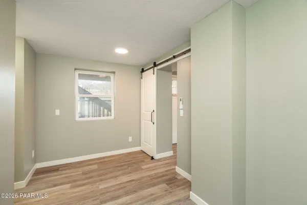 a view of an empty room with wooden floor and a window