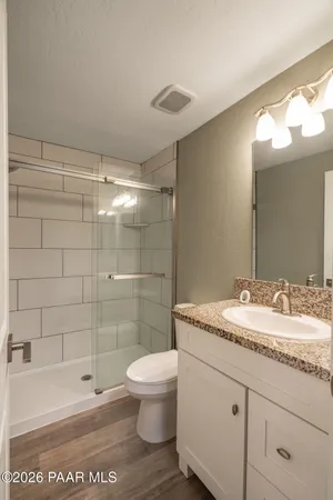 a bathroom with a granite countertop sink a toilet and shower