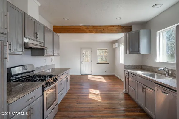 a kitchen with granite countertop a sink cabinets and stainless steel appliances