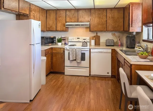 a kitchen with a white cabinets a sink dishwasher a refrigerator and a stove with wooden floor