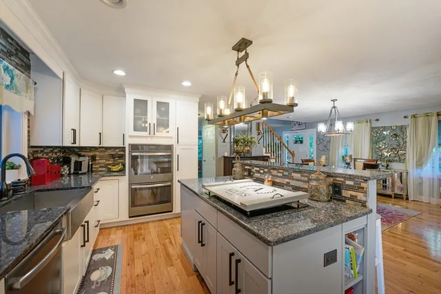 a kitchen with granite countertop kitchen island stainless steel appliances a sink stove and refrigerator