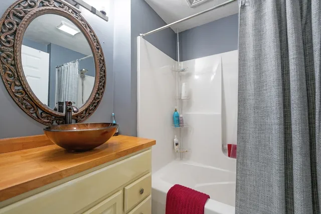 a bathroom with a granite countertop sink a mirror and bathtub