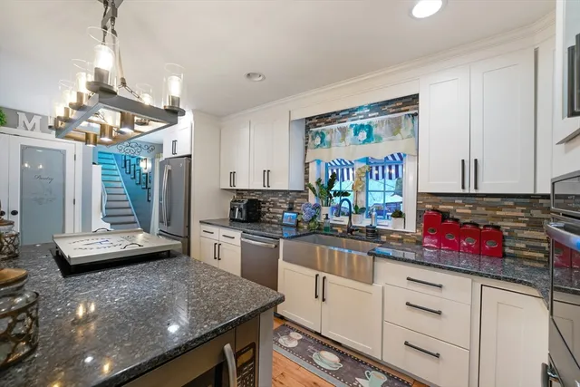 a kitchen with stainless steel appliances granite countertop a sink dishwasher and white cabinets with wooden floor
