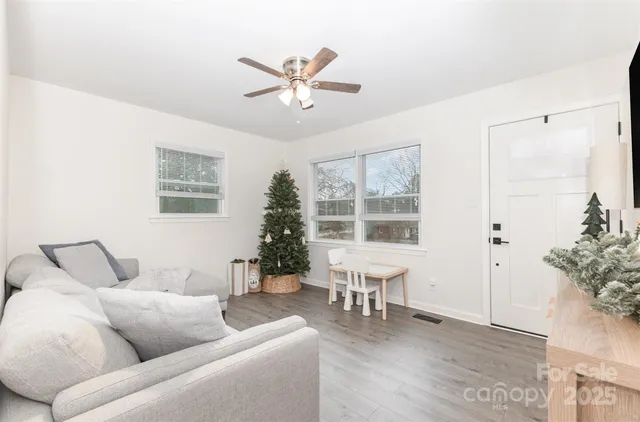 a living room with furniture and potted plants with wooden floor