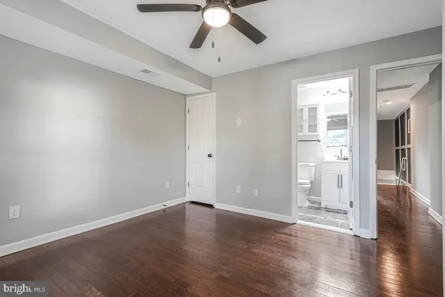 a view of an empty room with wooden floor and a ceiling fan