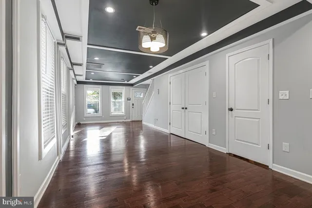a view of an empty room with wooden floor and windows