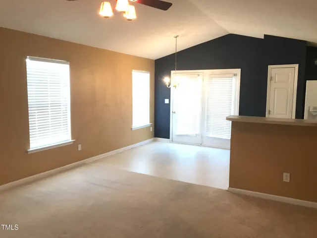 a view of an empty room with window and a kitchen