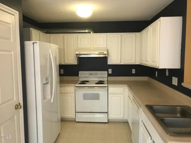 a kitchen with a refrigerator sink and cabinets