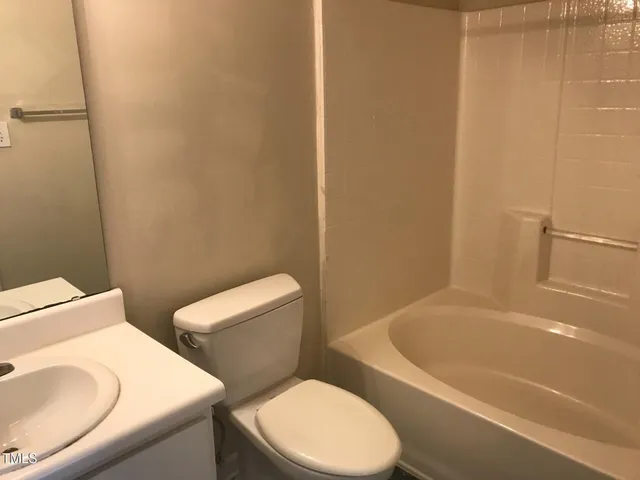 a white toilet and tub sitting next to a bathroom sink