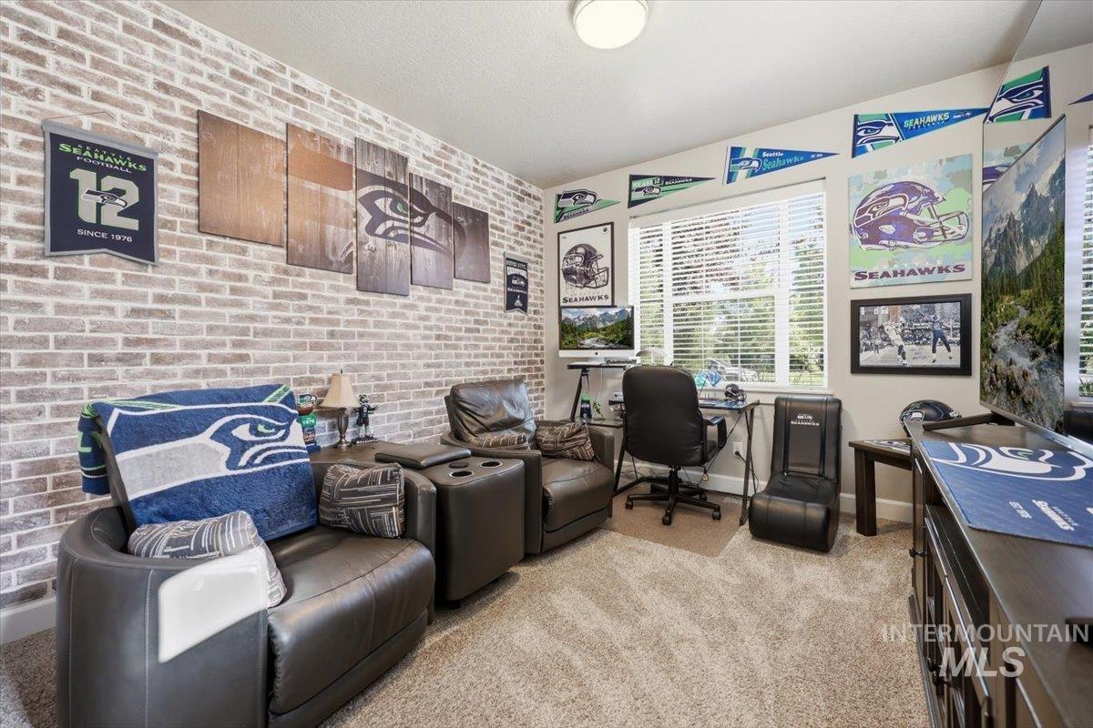 1303 West Brando Street Meridian, ID 83646 - Photo 9 of 49 Room featuring a brick-finish accent wall, neutral carpeting, and a large window with horizontal blinds