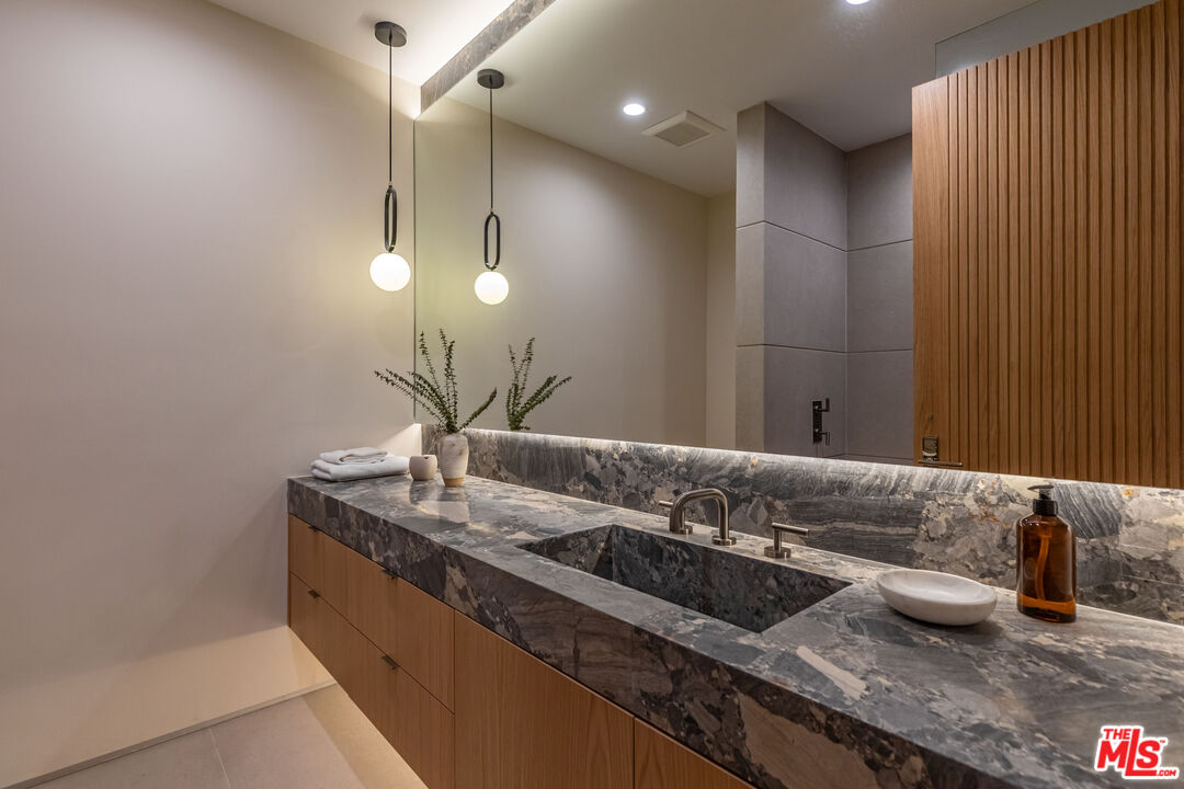 1705 Carla Ridge Beverly Hills, CA 90210 - Photo 24 of 53 a bathroom with a granite countertop sink a mirror and vanity