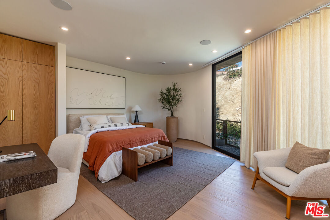 1705 Carla Ridge Beverly Hills, CA 90210 - Photo 27 of 53 a spacious bedroom with a bed and glass window
