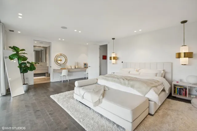 a spacious bedroom with a bed a couch and a potted plant