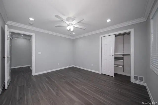 an empty room with wooden floor closet and windows