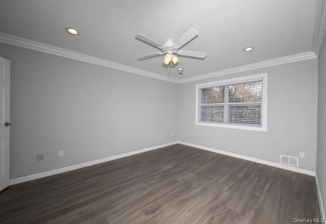 an empty room with wooden floor ceiling fan and windows