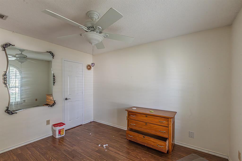 6504 Johnnie Street Watauga, TX 76148 - Photo 15 of 23 Wood-finish flooring with white baseboards, a white ceiling fan, and a white paneled door