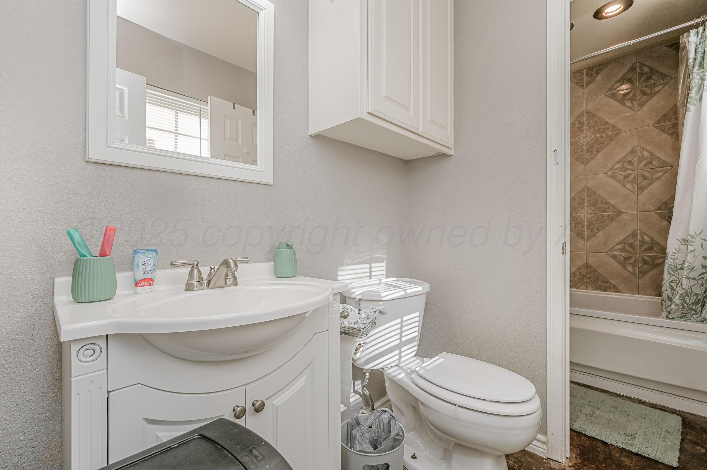 4351 South Tyler Street Amarillo, TX 79110 - Photo 13 of 18 a bathroom with a sink a toilet and a window