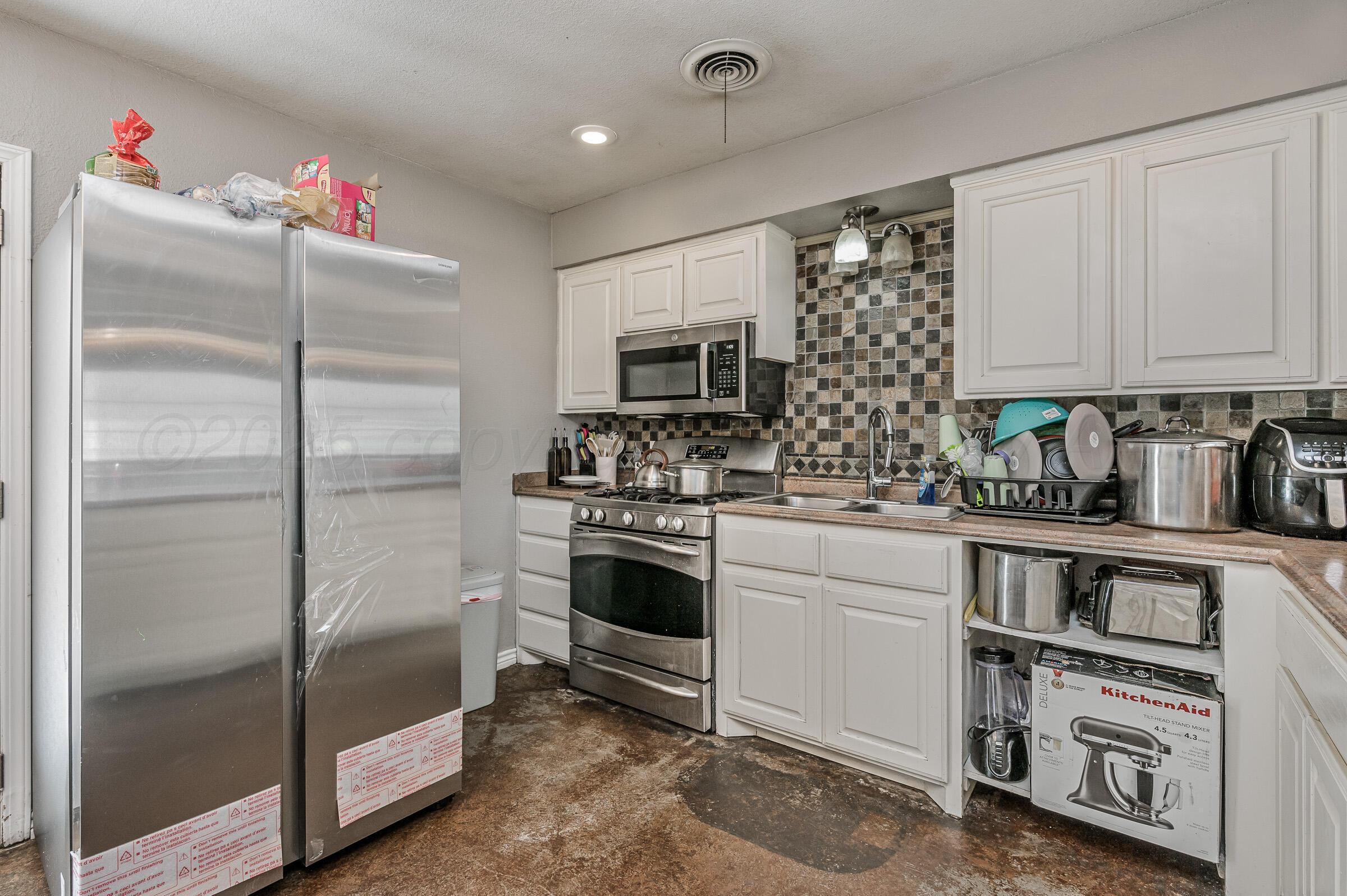 4351 South Tyler Street Amarillo, TX 79110 - Photo 7 of 18 a kitchen with a refrigerator and white cabinets